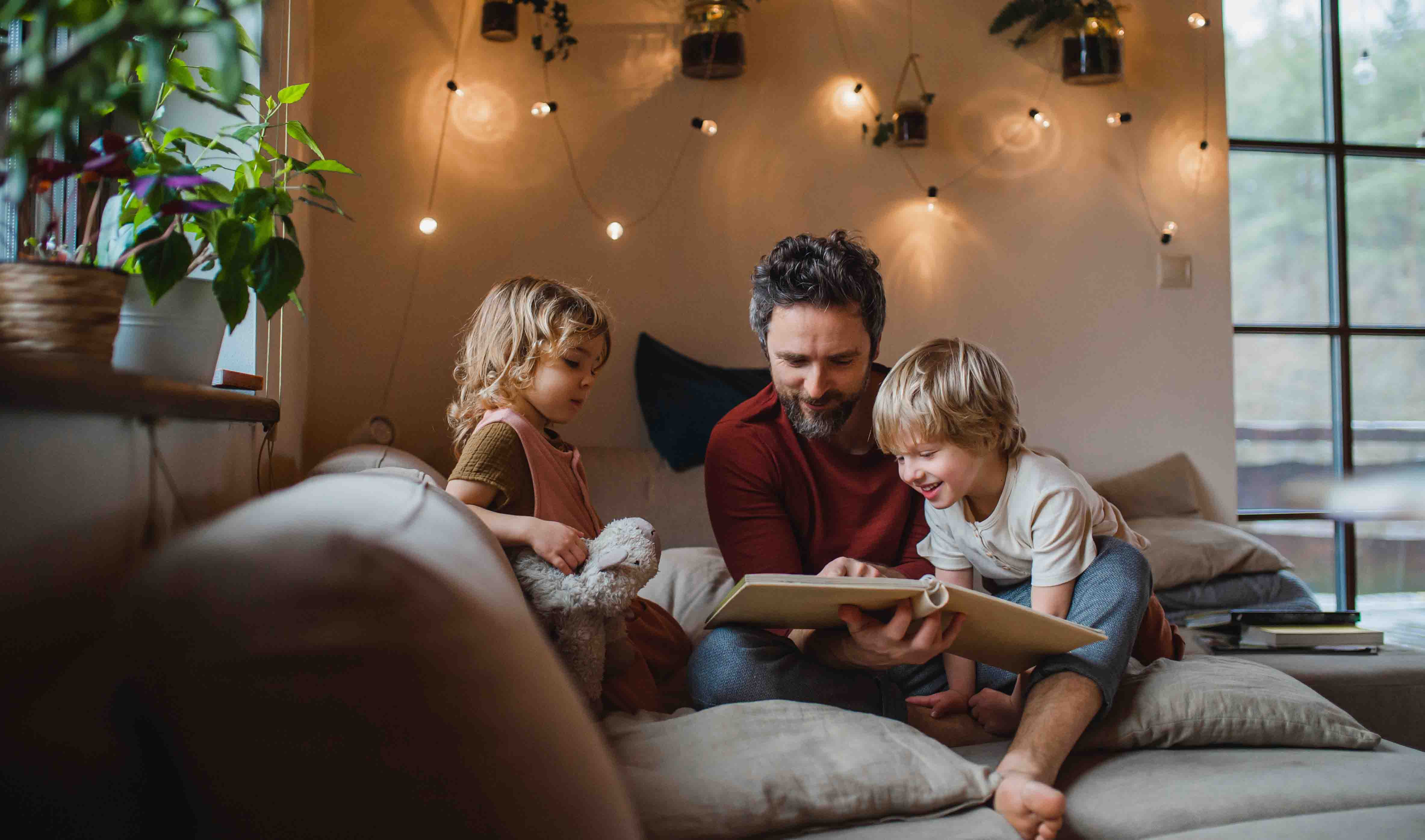 man met twee kinderen boek aan het lezen op de bank